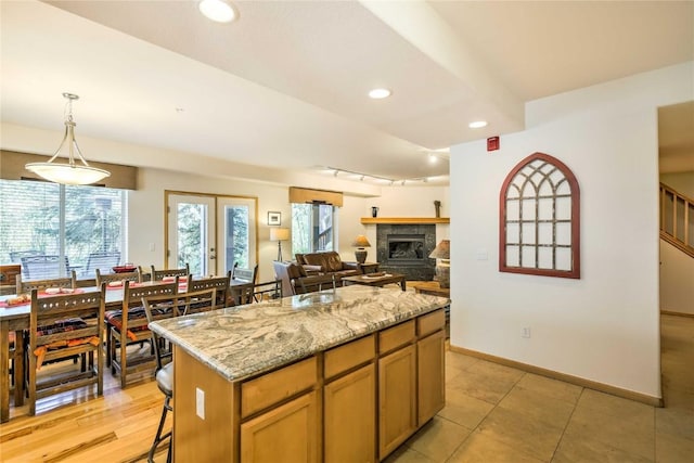 233 Creekside Dr Unit 104, Frisco, CO 80443 - kitchen with light stone countertops, a healthy amount of sunlight, decorative light fixtures, and a kitchen island