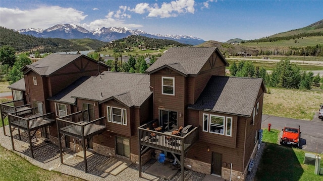 74 Stag Trl Unit 74, Dillon, CO 80435 - back of property featuring a shingled roof, stone siding, and a deck with mountain view