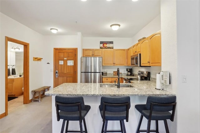 22714 US Highway 6 Unit 5941, Keystone, CO 80435 - kitchen featuring light stone countertops, a sink, a kitchen breakfast bar, stainless steel appliances, and a peninsula