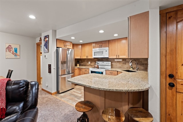 433 Wild Irishman Rd Unit 1039, Keystone, CO 80435 - kitchen featuring white appliances, a sink, a peninsula, a kitchen bar, and light stone counters