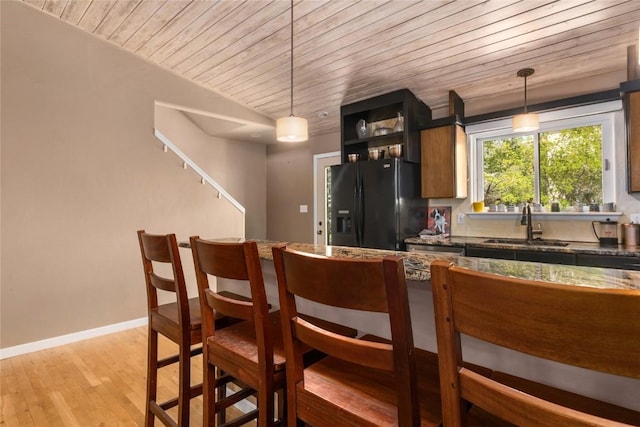 3432 Flagstone Ct, Steamboat Springs, CO 80487 - kitchen featuring black fridge, wood ceiling, a sink, light wood finished floors, and a kitchen bar