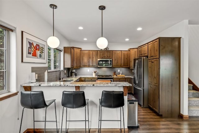 459 Willett Heights Ct, Steamboat Springs, CO 80487 - kitchen featuring appliances with stainless steel finishes, a sink, a peninsula, dark wood-type flooring, and tasteful backsplash