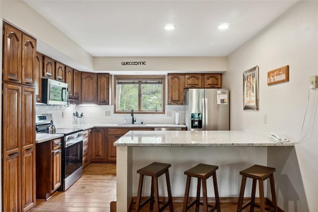 23177 Barbour Dr Unit 14, Keystone, CO 80435 - kitchen featuring stainless steel appliances, a peninsula, a breakfast bar area, light stone countertops, and recessed lighting