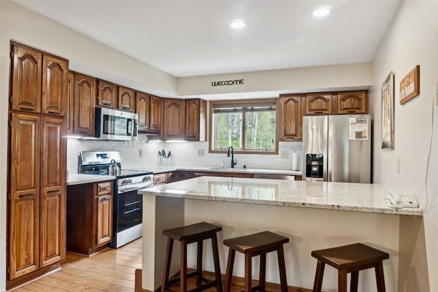 23177 Barbour Dr Unit 14, Keystone, CO 80435 - kitchen with stainless steel appliances, a peninsula, light stone countertops, a kitchen breakfast bar, and recessed lighting