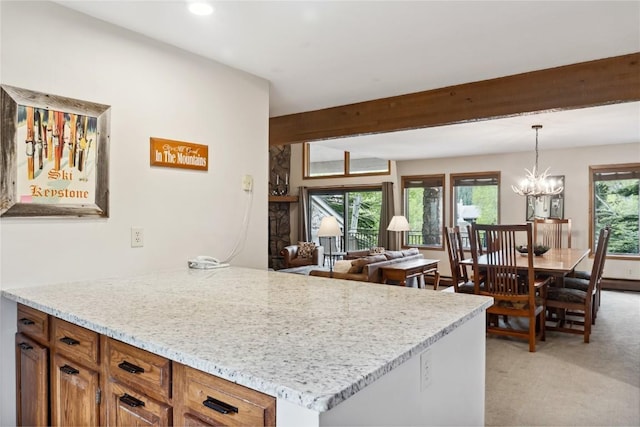 23177 Barbour Dr Unit 14, Keystone, CO 80435 - kitchen with beamed ceiling, light carpet, brown cabinetry, decorative light fixtures, and light stone counters