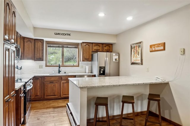 23177 Barbour Dr Unit 14, Keystone, CO 80435 - kitchen with appliances with stainless steel finishes, a peninsula, light wood finished floors, light stone countertops, and baseboard heating