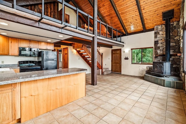 243 Lone Hand Way, Breckenridge, CO 80424 - kitchen with black appliances, a wood stove, light tile patterned floors, high vaulted ceiling, and tile countertops