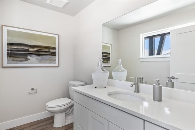 bathroom featuring wood finished floors, vanity, toilet, and baseboards