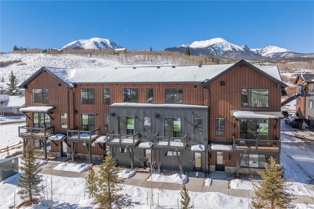 snow covered rear of property featuring a mountain view