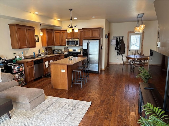 2379 Abbey Ct Unit 3, Steamboat Springs, CO 80487 - kitchen featuring appliances with stainless steel finishes, a kitchen island, a kitchen bar, decorative light fixtures, and dark wood-style flooring