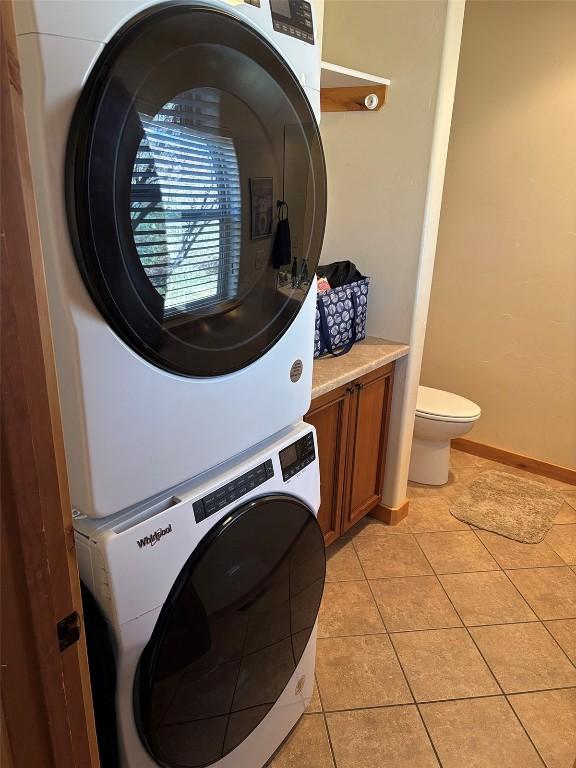 2379 Abbey Ct Unit 3, Steamboat Springs, CO 80487 - laundry room featuring stacked washer / dryer, light tile patterned floors, and baseboards