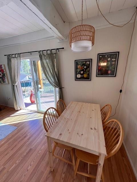 dining area featuring wood finished floors, baseboards, and beam ceiling