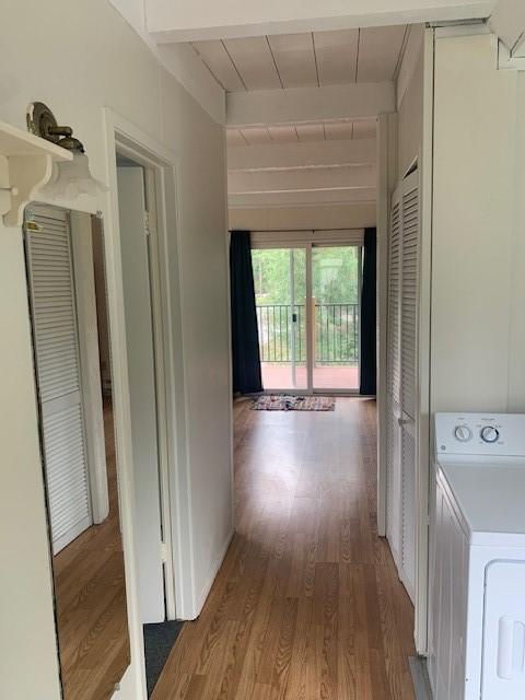 hallway with washer / dryer, wood finished floors, and beam ceiling
