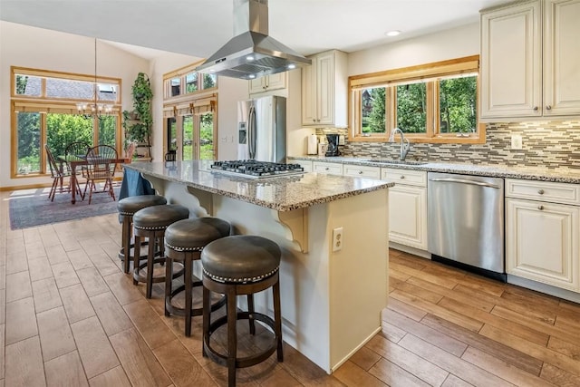 12 Raindance Trl, Dillon, CO 80435 - kitchen featuring appliances with stainless steel finishes, island range hood, light wood-type flooring, light stone counters, and a kitchen bar