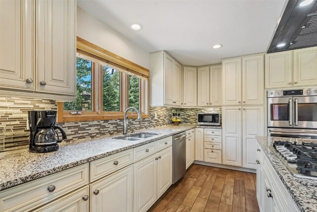 12 Raindance Trl, Dillon, CO 80435 - kitchen with stainless steel appliances, ventilation hood, light wood-type flooring, tasteful backsplash, and light stone counters