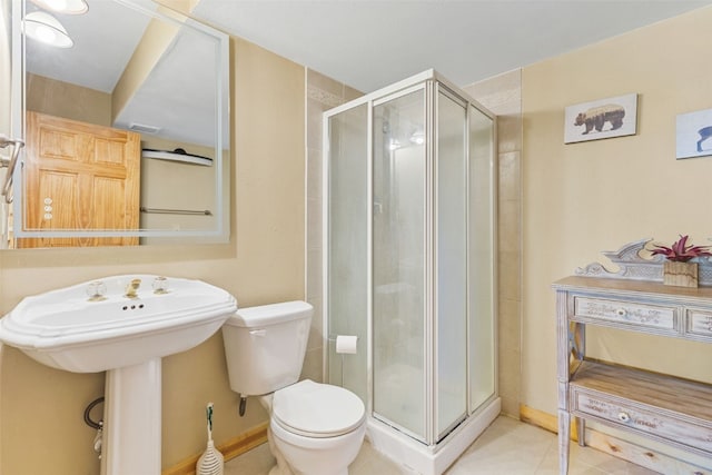 bathroom featuring tile patterned floors, toilet, and a shower with shower door