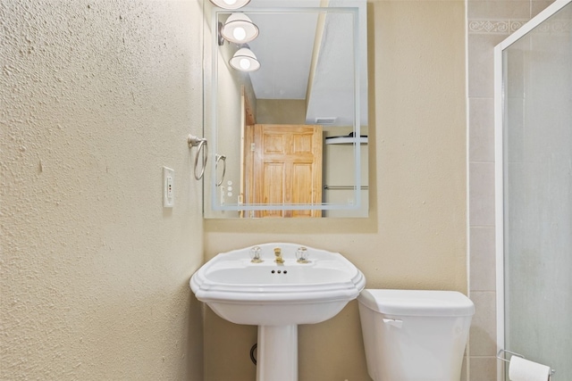 bathroom featuring toilet and an enclosed shower