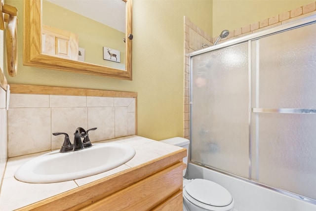 full bathroom with vanity, toilet, decorative backsplash, and bath / shower combo with glass door