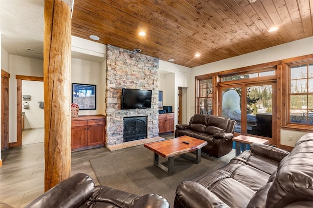 living room featuring recessed lighting, a stone fireplace, wood finished floors, wooden ceiling, and ornate columns