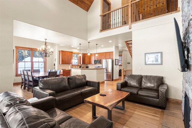 living area with high vaulted ceiling, recessed lighting, a notable chandelier, baseboards, and light wood-type flooring