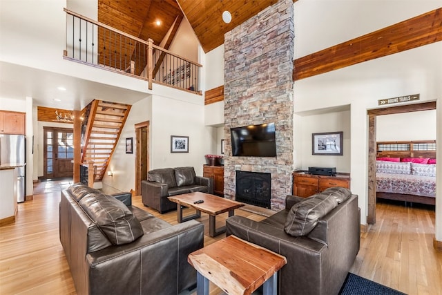 living room featuring baseboards, wood ceiling, stairway, light wood-style floors, and a fireplace