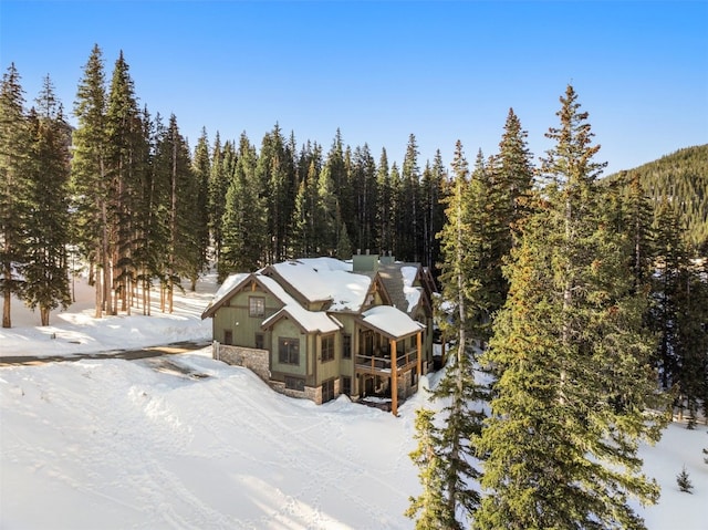 snowy aerial view with a wooded view