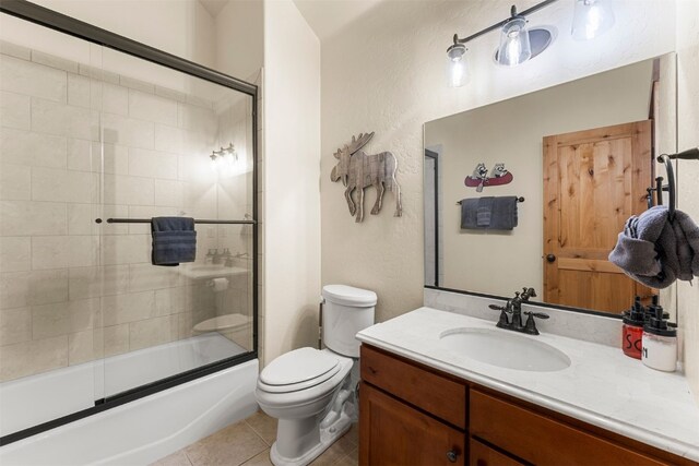 bathroom featuring combined bath / shower with glass door, vanity, toilet, and tile patterned floors