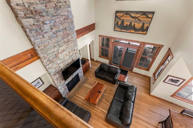 living room with a towering ceiling, a fireplace, and wood finished floors