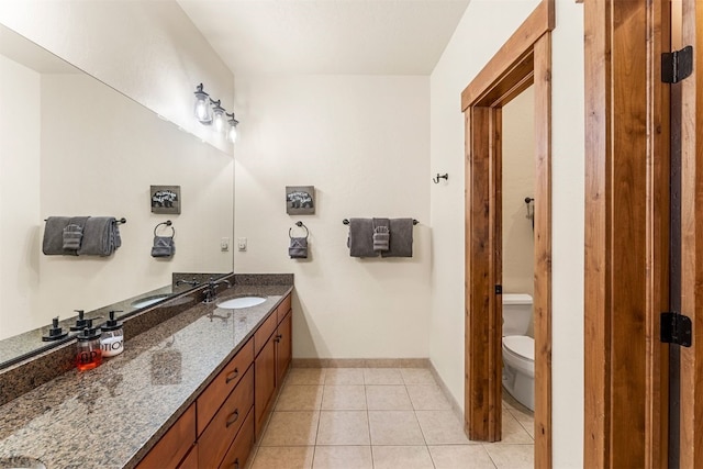 bathroom featuring baseboards, vanity, toilet, and tile patterned floors