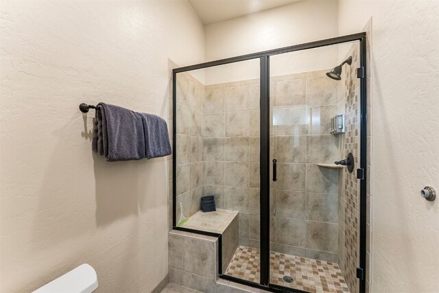 full bathroom featuring a stall shower and a textured wall