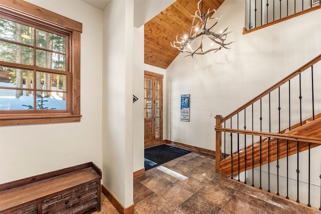 foyer entrance with a notable chandelier, wood ceiling, baseboards, stairs, and vaulted ceiling