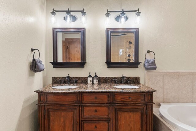 full bath featuring double vanity, a sink, and a bathtub