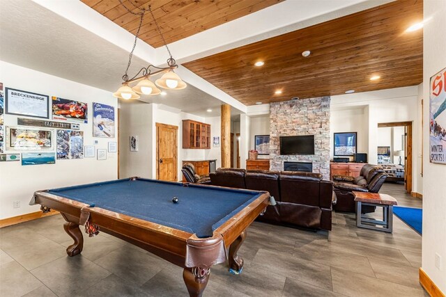 recreation room featuring baseboards, wooden ceiling, tile patterned floors, a stone fireplace, and recessed lighting