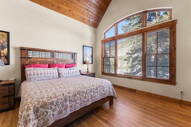 bedroom featuring high vaulted ceiling, baseboards, and wood finished floors