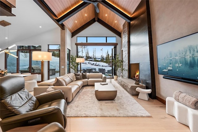 interior space with wood ceiling, beam ceiling, high vaulted ceiling, a large fireplace, and light wood-type flooring