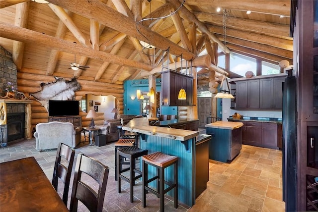 kitchen with wooden ceiling, beamed ceiling, a stone fireplace, log walls, and butcher block countertops