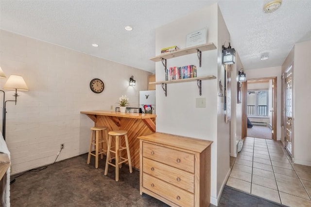 kitchen featuring brick wall, butcher block counters, a breakfast bar, a textured ceiling, and open shelves