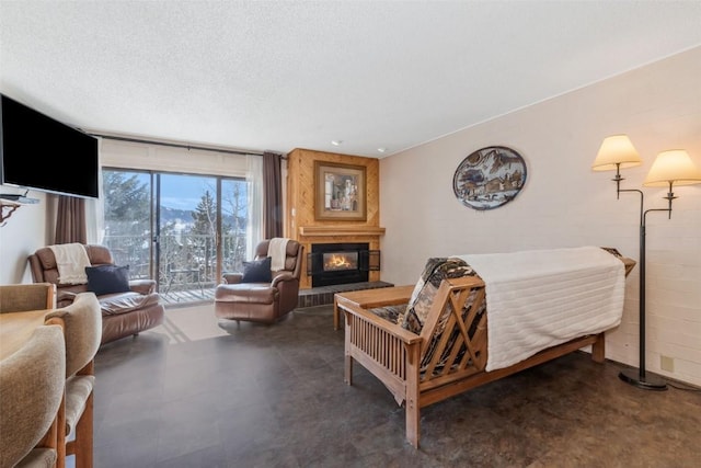 living area with a textured ceiling and a glass covered fireplace