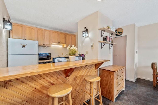 kitchen with a breakfast bar area, open shelves, light brown cabinetry, freestanding refrigerator, and black microwave