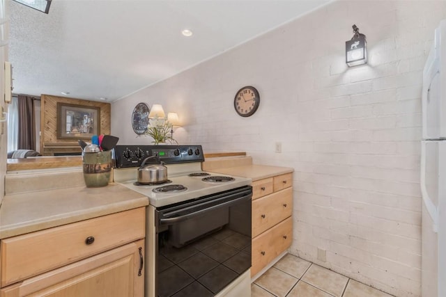 kitchen featuring light tile patterned floors, brick wall, range with electric stovetop, light countertops, and light brown cabinetry