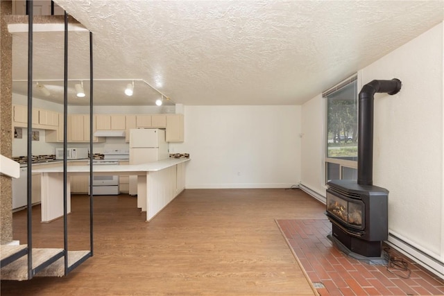 kitchen with white appliances, a textured ceiling, a baseboard radiator, and a wood stove