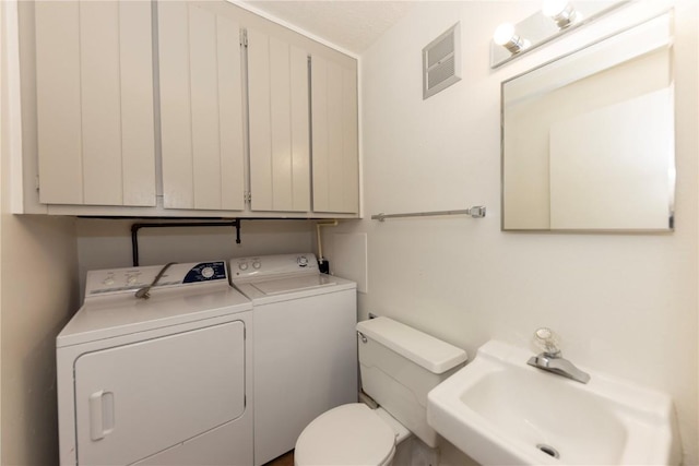 bathroom with toilet, sink, and washing machine and clothes dryer