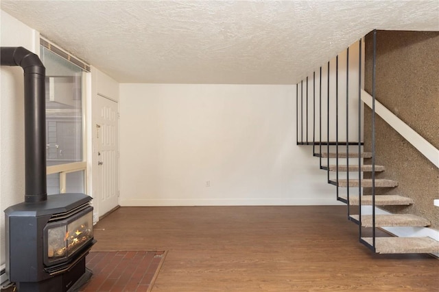 basement with a textured ceiling, a wood stove, and dark wood-type flooring