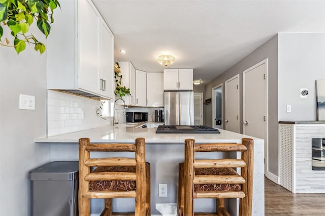 kitchen with white cabinets, dark wood-type flooring, stainless steel appliances, tasteful backsplash, and kitchen peninsula