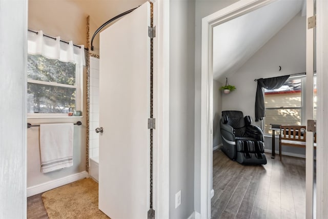 bathroom with bathtub / shower combination, hardwood / wood-style floors, and lofted ceiling