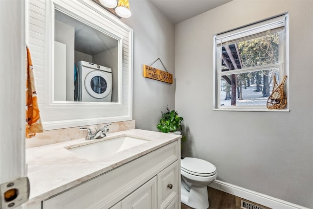 bathroom with vanity, toilet, hardwood / wood-style floors, and stacked washer / dryer