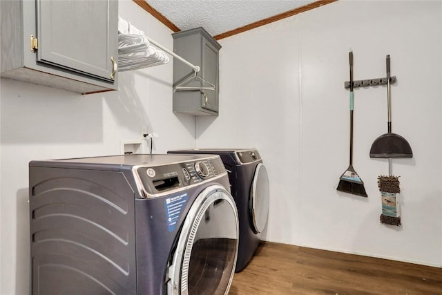 washroom with cabinets, a textured ceiling, dark wood-type flooring, crown molding, and washing machine and clothes dryer