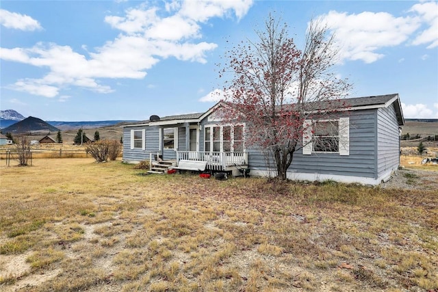 back of house featuring a yard and a deck with mountain view