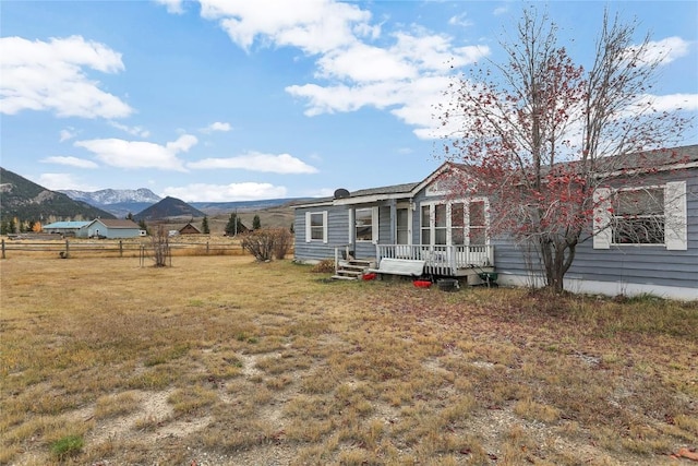 rear view of house with a deck with mountain view and a lawn