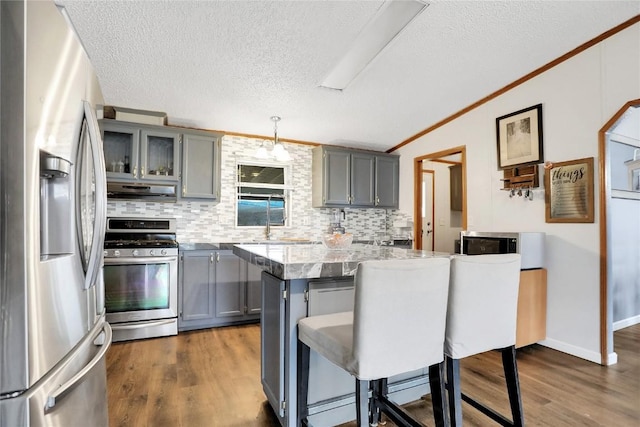 kitchen featuring a breakfast bar area, gray cabinets, decorative light fixtures, and appliances with stainless steel finishes